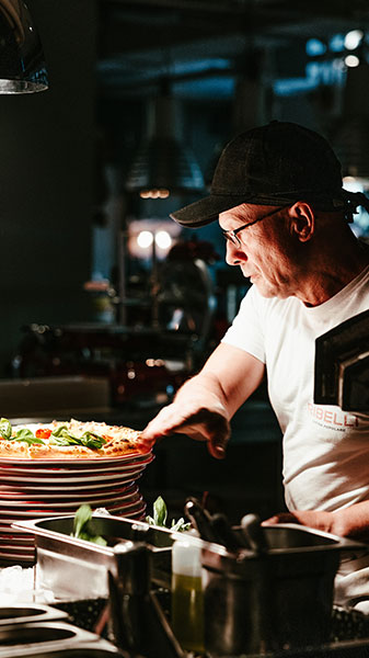 A piazziolo working on a pizza with tomatoes and basil at the RIBELLI restaurant