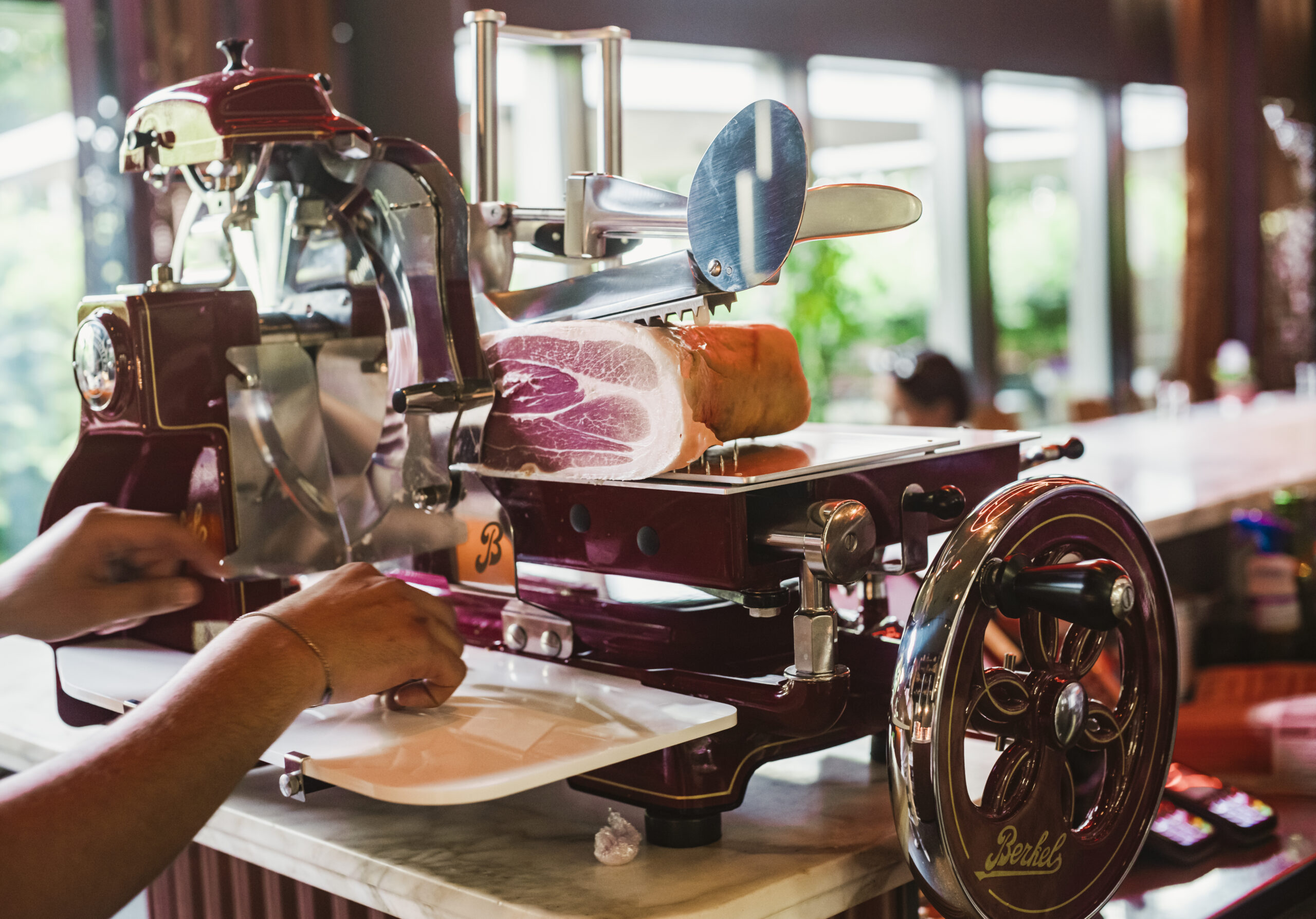 A Berkel slicing machine with a ham on it, slicing fresh ham in the RIBELLI restaurant