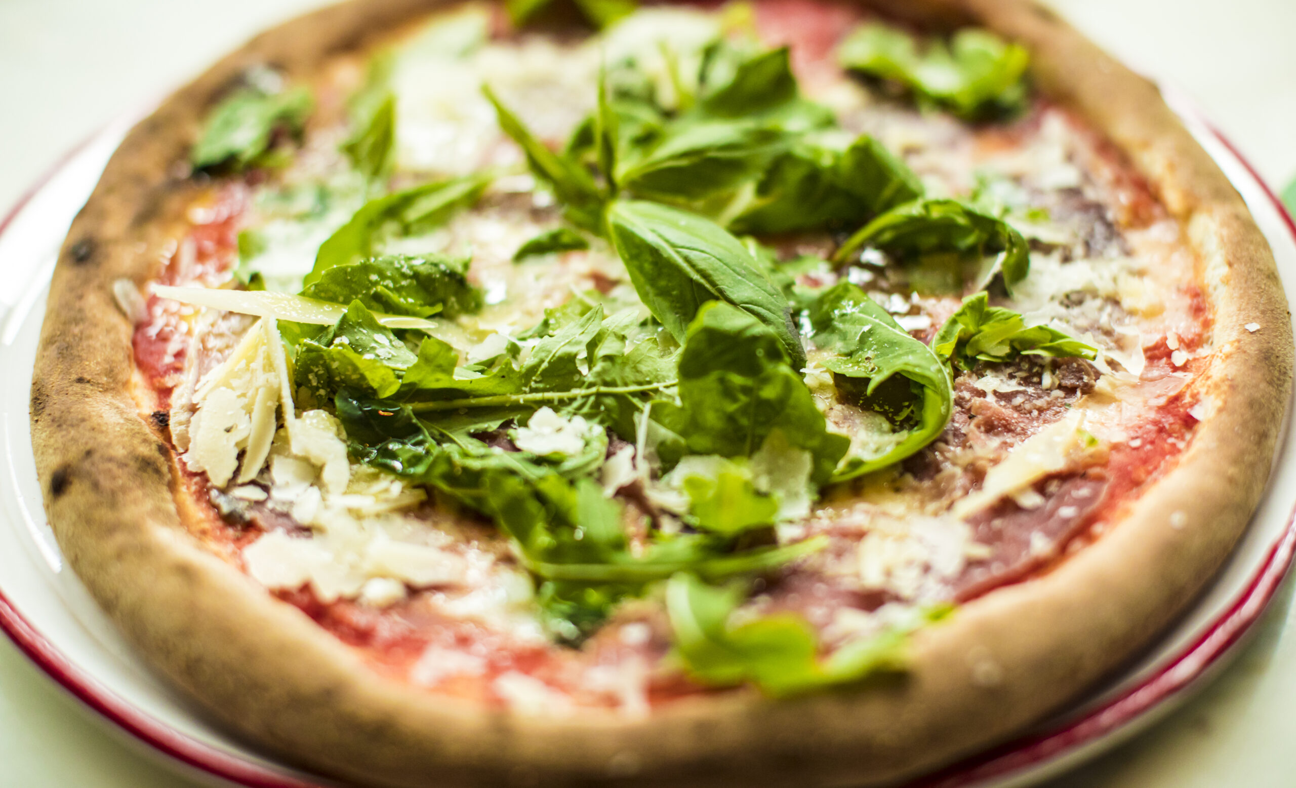 An Italian pizza with rocket, prosciutto and parmeggiano
