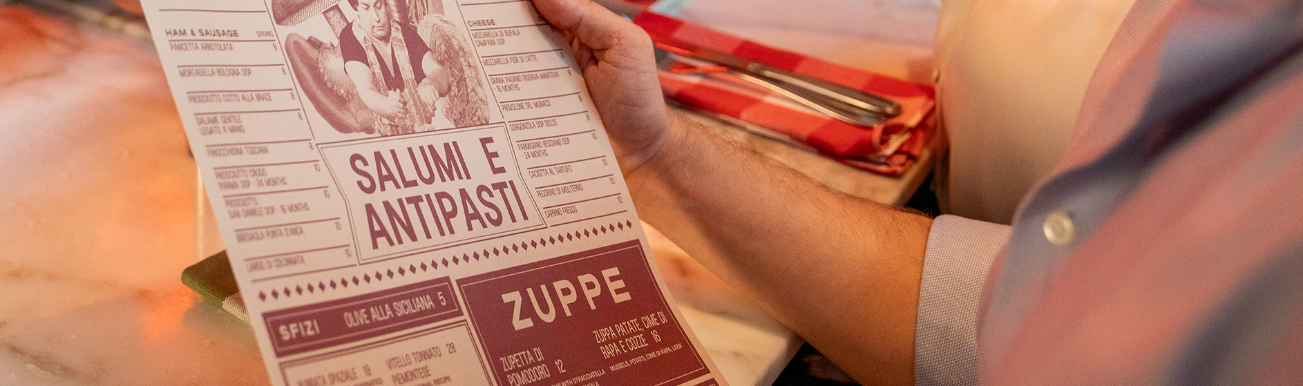 A guest holding the menu, which is printed in newspaper style